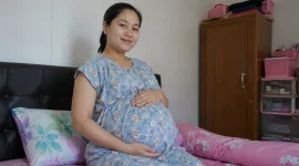 Seorang ibu hamil sedang menunjukkan kondisi kehamilannya. (Satuteks.com)