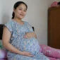 Seorang ibu hamil sedang menunjukkan kondisi kehamilannya. (Satuteks.com)