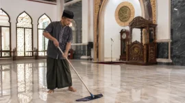 Seorang marbot sedang membersihkan masjid. (AI)