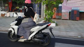 Ilustrasi seorang perempuan mengendarai motor matik. (Foto: Pexels)